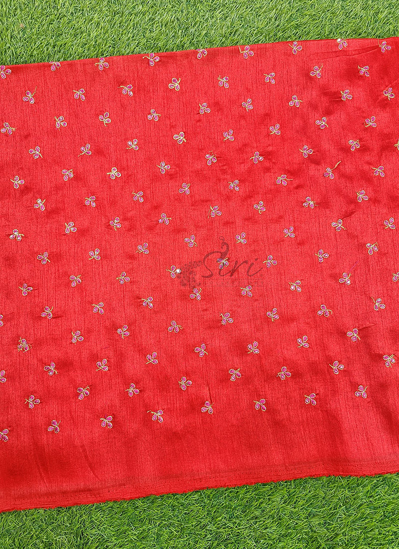 Red fabric with white floral patterns on a green grass background